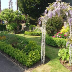 Box hedges with herbaceous planting and an arch brings timeless style to this front garden in Frittenden